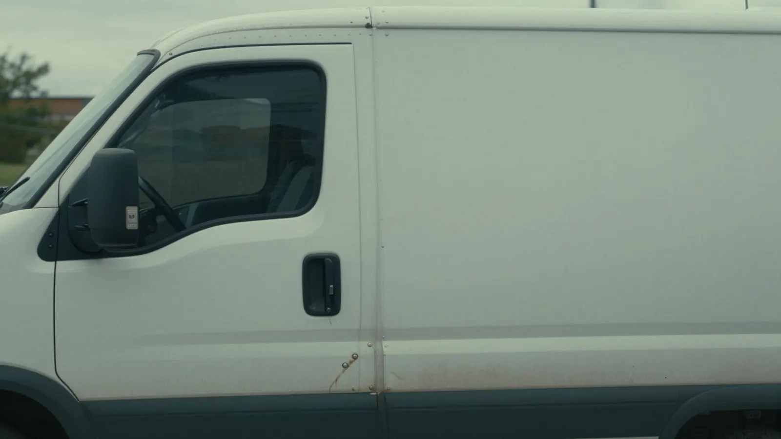 The blank driver's door of a white commercial box truck in overcast daylight
